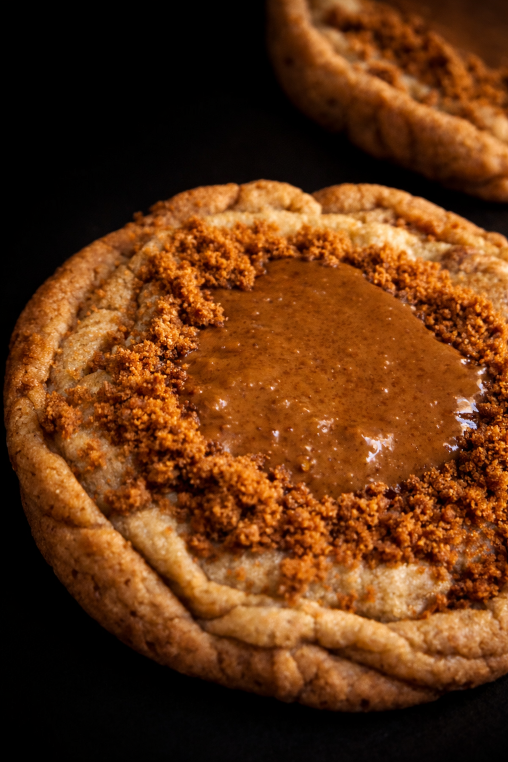 Close-up of a cookie with a brown filling on a dark background